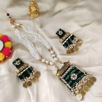 A handmade green bandhani fabric necklace and earring set. Features white pearl strands, antique gold coin charms, and kundan work on a cream cloth.