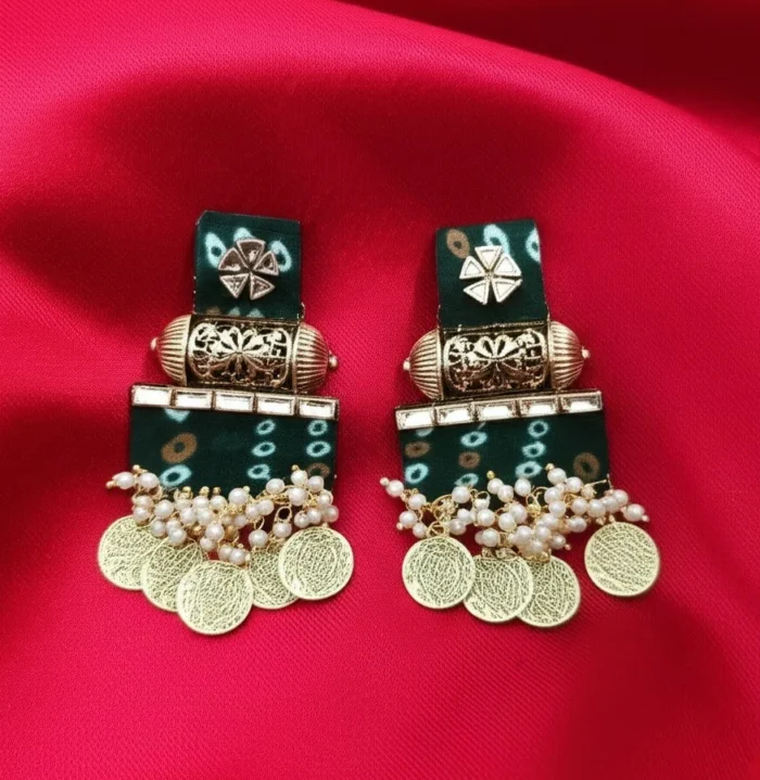 A pair of traditional green earrings with a white Bandhani tie-dye print, decorated with kundan work and hanging gold temple coins.
