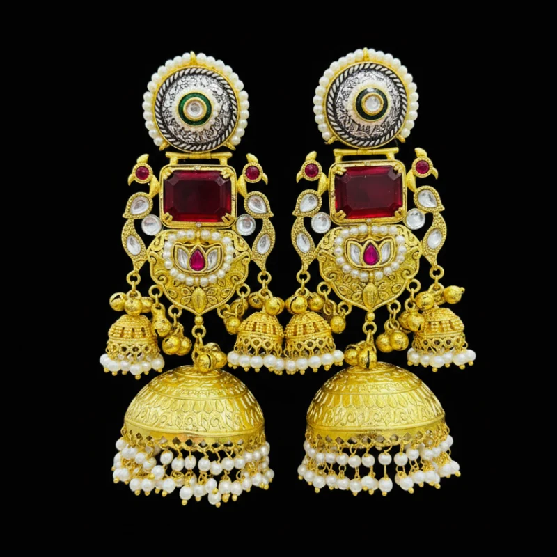 A pair of grand gold tone jhumka earrings with rectangular ruby red stones, preacock design, green enamel, and pearl detailing Black Background