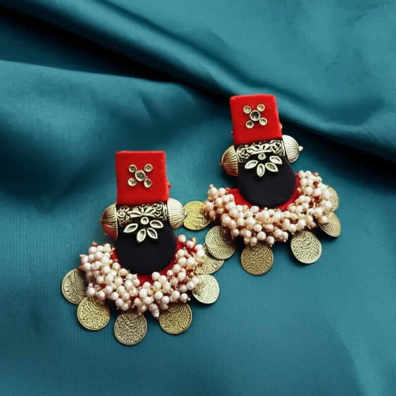 A pair of red and black fabric statement earrings with floral kundan motifs and dangles of antique gold coins and pearls.