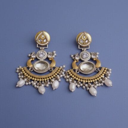 A pair of gold and silver Chandbali earrings with white pearls, a large translucent oval stone, and smaller white diamonds on a black background.