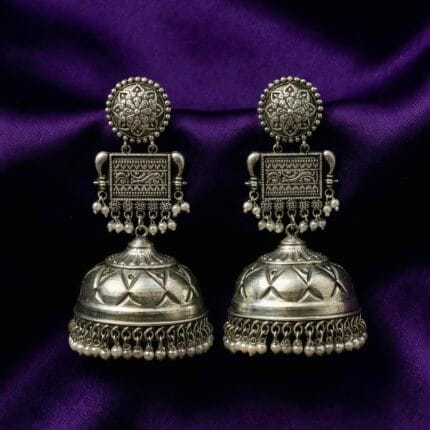 Traditional Oxidized Jhumka Earrings with Pearls placed on blueish purple silk cloth