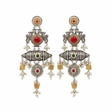 A pair of detailed traditional silver look earrings with red and green stones, white pearls, and gold accents on a white background