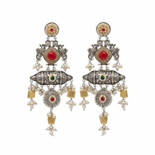 A pair of detailed traditional silver look earrings with red and green stones, white pearls, and gold accents on a white background