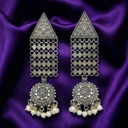 Pair of oxidized silver look triangle jhumka earrings with white pearl drops on blueish purple silk cloth