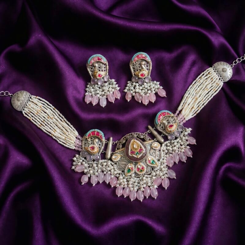 Traditional oxidized silver necklace and earring set with white pearls, rose quartz beads, and colorful enamel accents, displayed on purple satin fabric