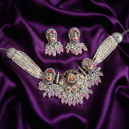 Traditional oxidized silver necklace and earring set with white pearls, rose quartz beads, and colorful enamel accents, displayed on purple satin fabric