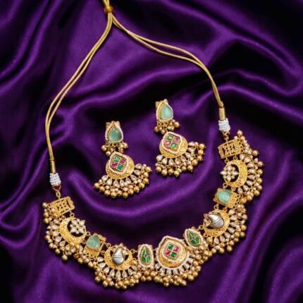 Matte gold-tone choker necklace with mint green teardrop stones and gold bead fringe on a purple silk background.