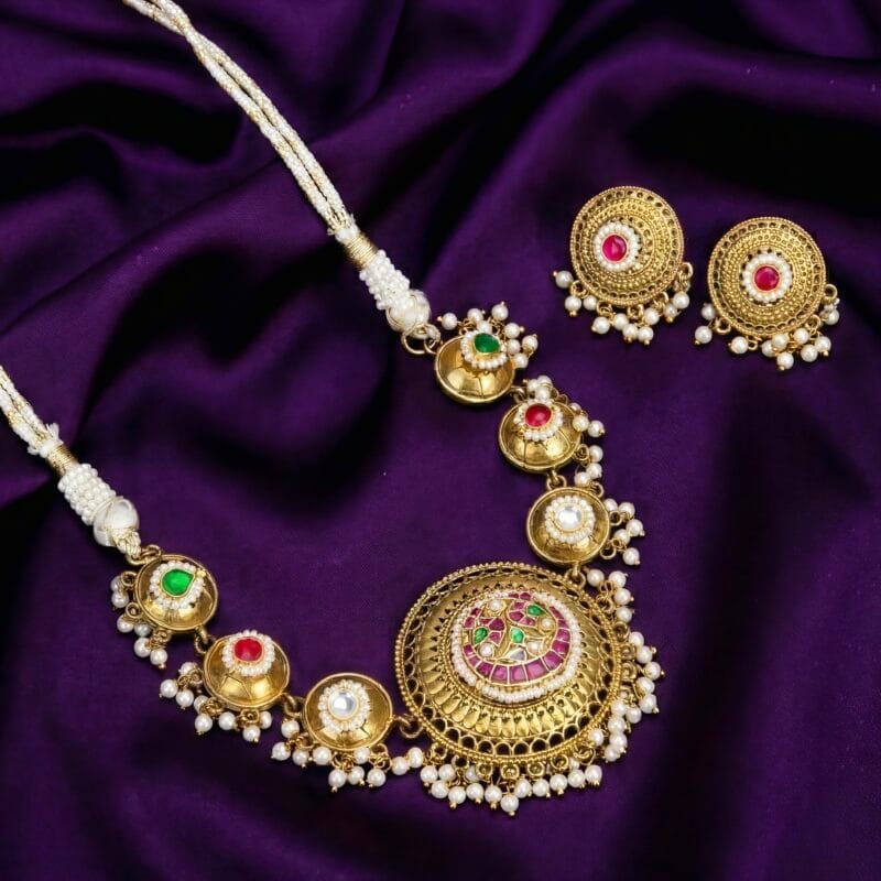 Golden Green choker necklace with red and green stones and small white pearl beads on a purple silk background.