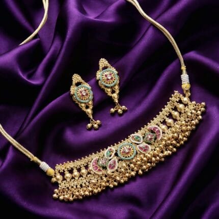 Gold-toned choker necklace and matching earrings with red and turquoise stones on purple silk