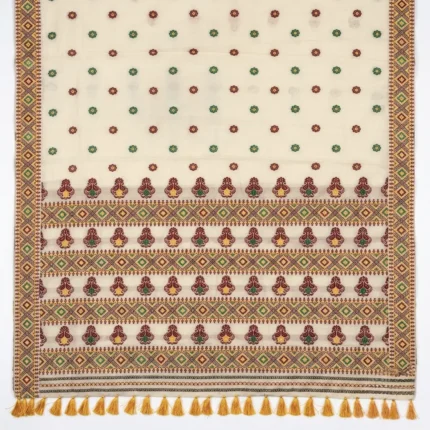 Closeup of off white bamboo cotton saree with green and maroon patterns and yellow tassels.