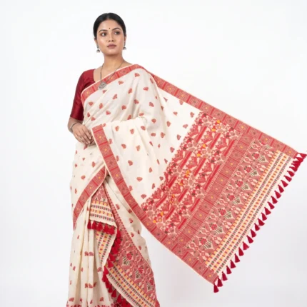 Model Wearing Assamese cream coloured saree with woven floral designs in red and yellow with large red tassels on border.