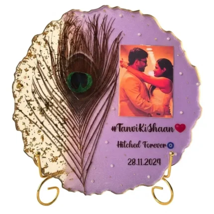 Metal stand with circular frame of lilac resin. Gold scalloped edges. Couple's photo and peacock feather.